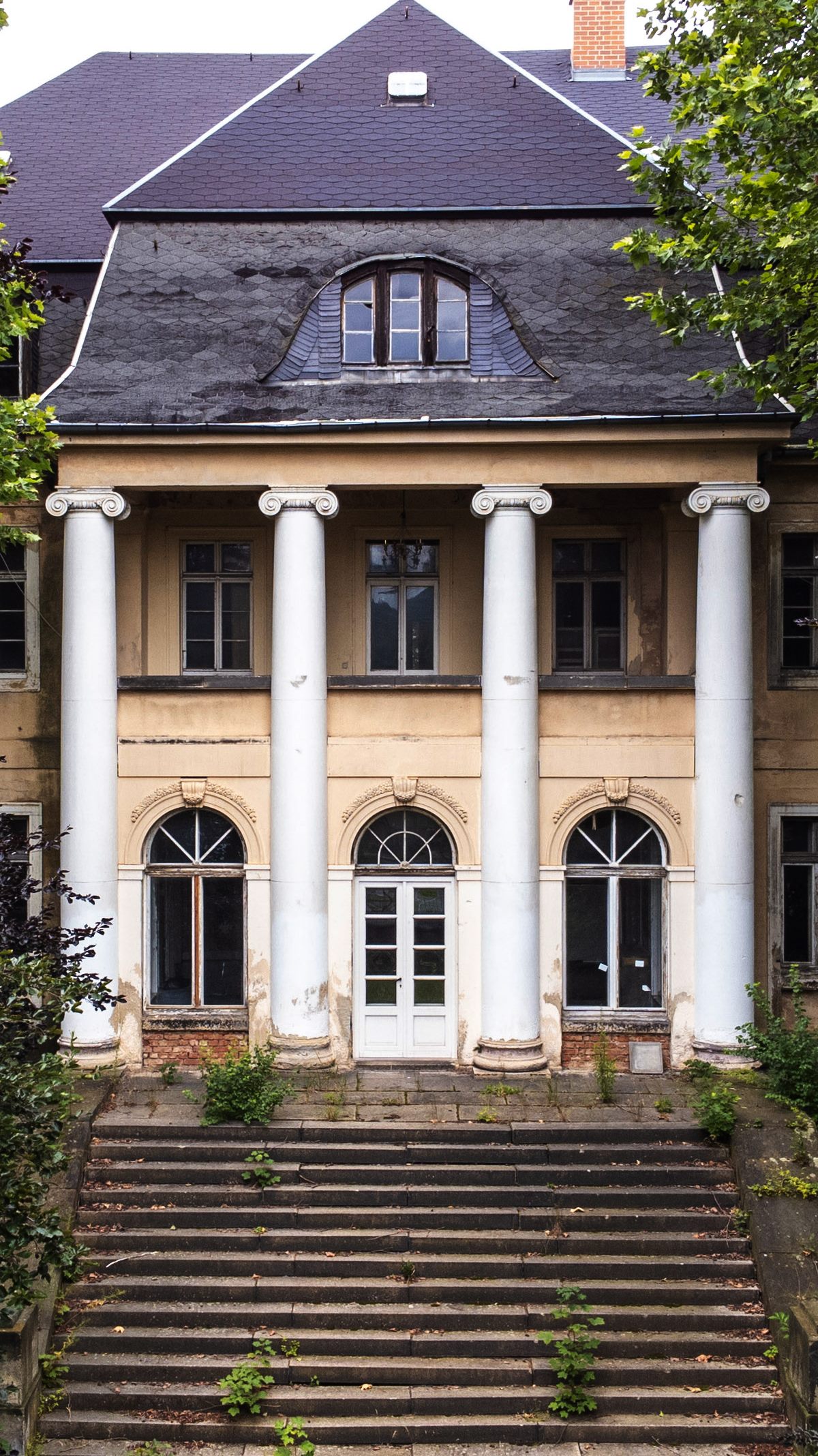 Die klassizistische Villa Bardzki mit vier Säulen und breiter, überwachsener Freitreppe