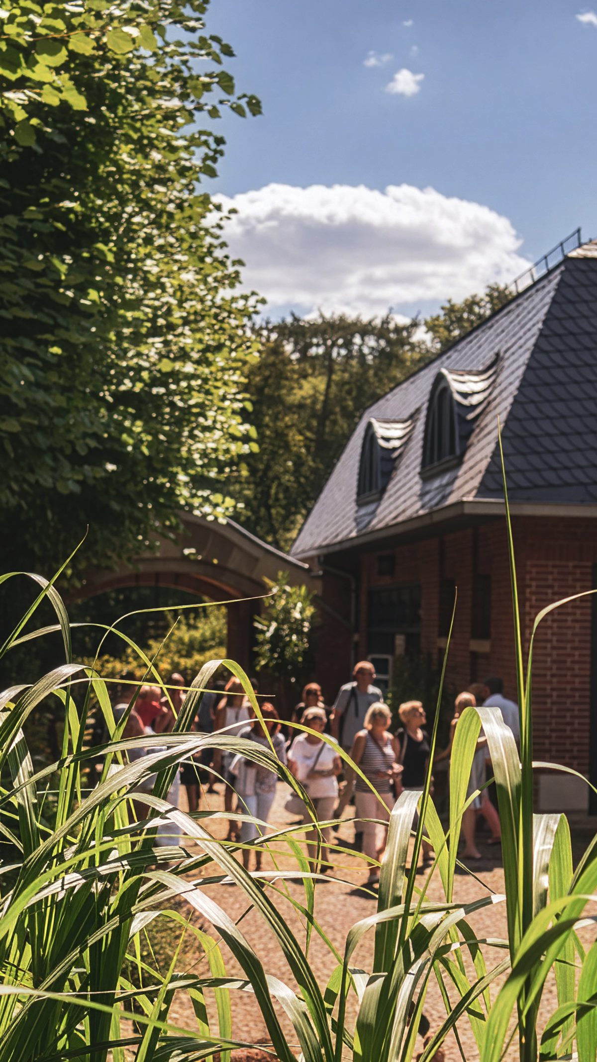 Besuchergruppe vor dem Backsteinbau von Haus Schulenburg an einem Sommertag