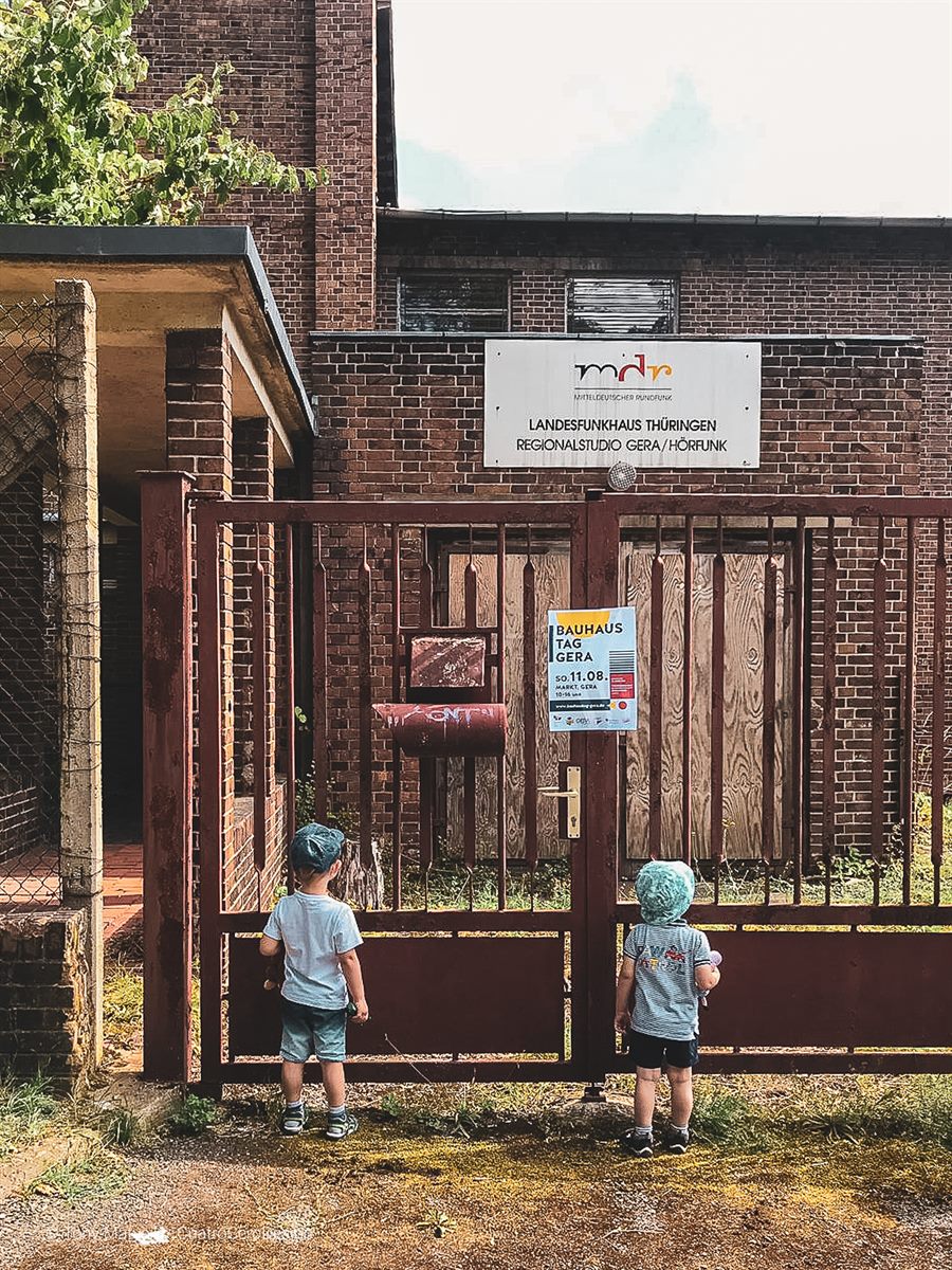 Zwei Kinder vor dem schmiedeeisernen Tor mit Bauhaustag-Plakat