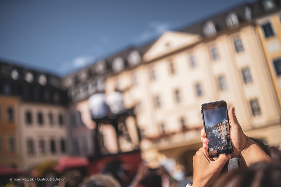 Durch ein Smartphone fotografiert: die Musikperformance auf dem Marktplatz im Hintergrund
