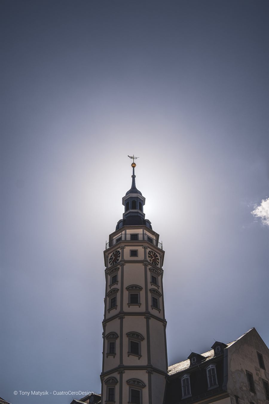 Kirchturm im Gegenlicht vor blauem Himmel